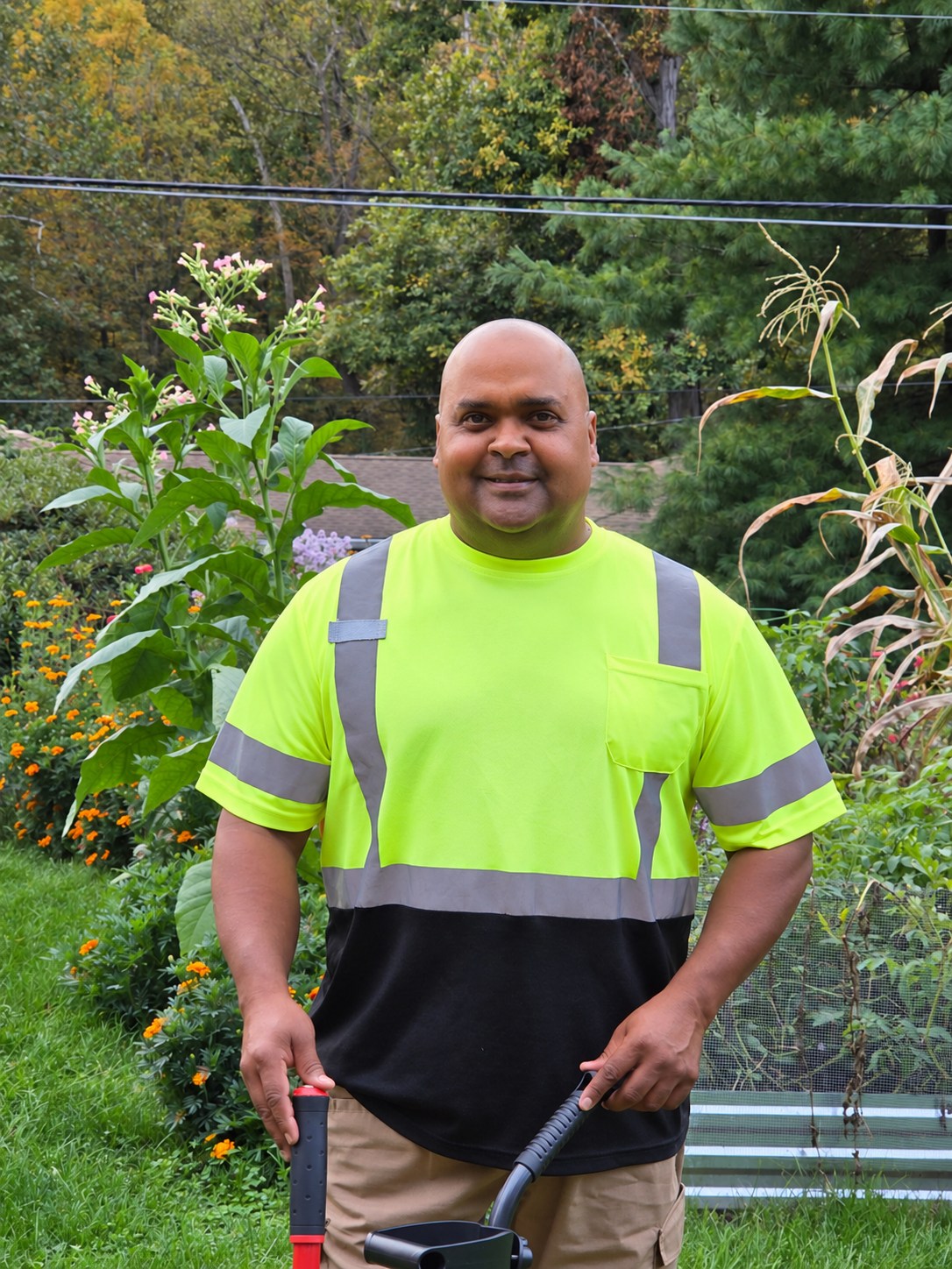David Flores standing in his high-visibility work shirt with his cleanup tools